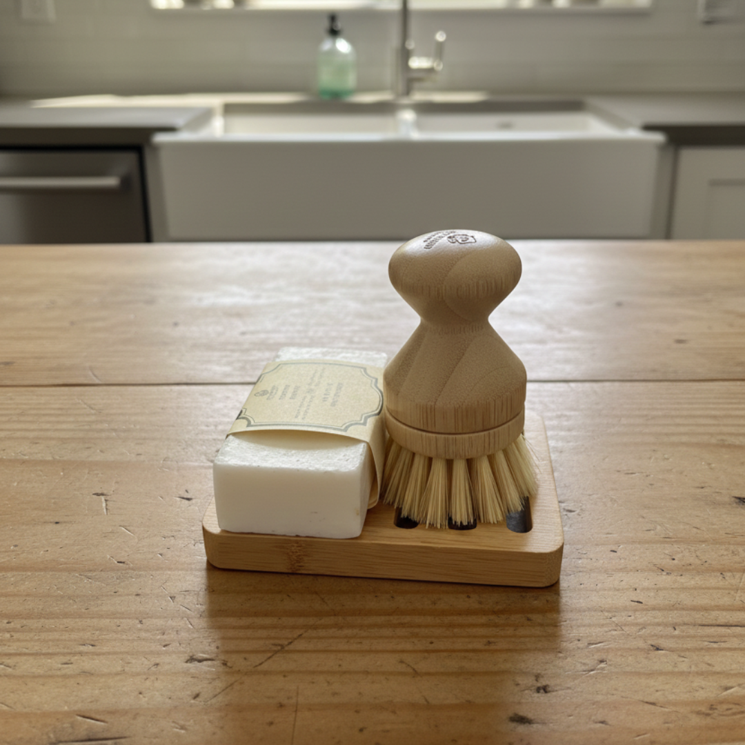 Bamboo dish brush and soap on a wooden surface with a kitchen background