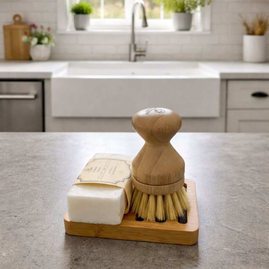 Bamboo dishwashing brush and soap on a kitchen counter with a window in the background