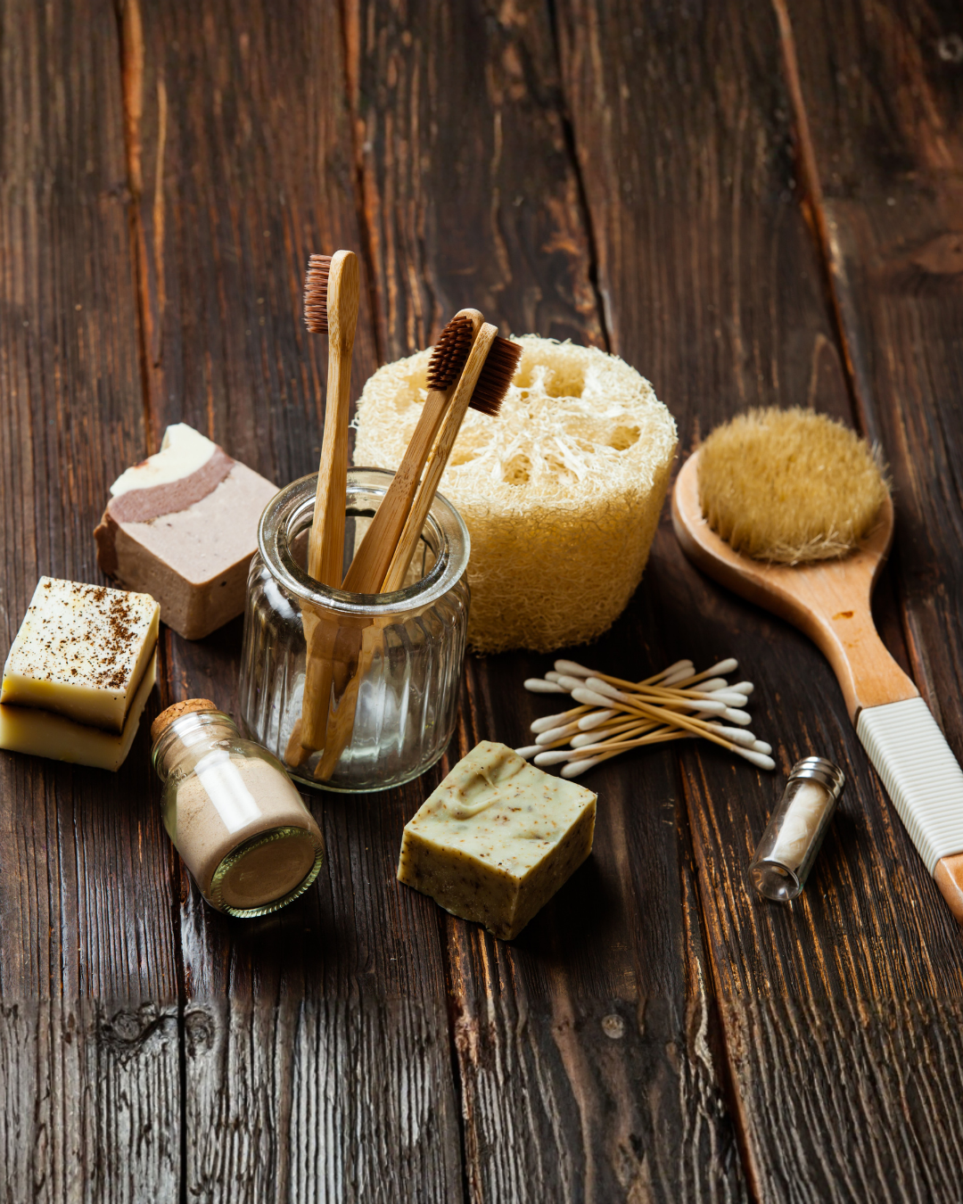 Collection of zero-waste products including bamboo toothbrushes, sponges, and soap on a wooden surface.