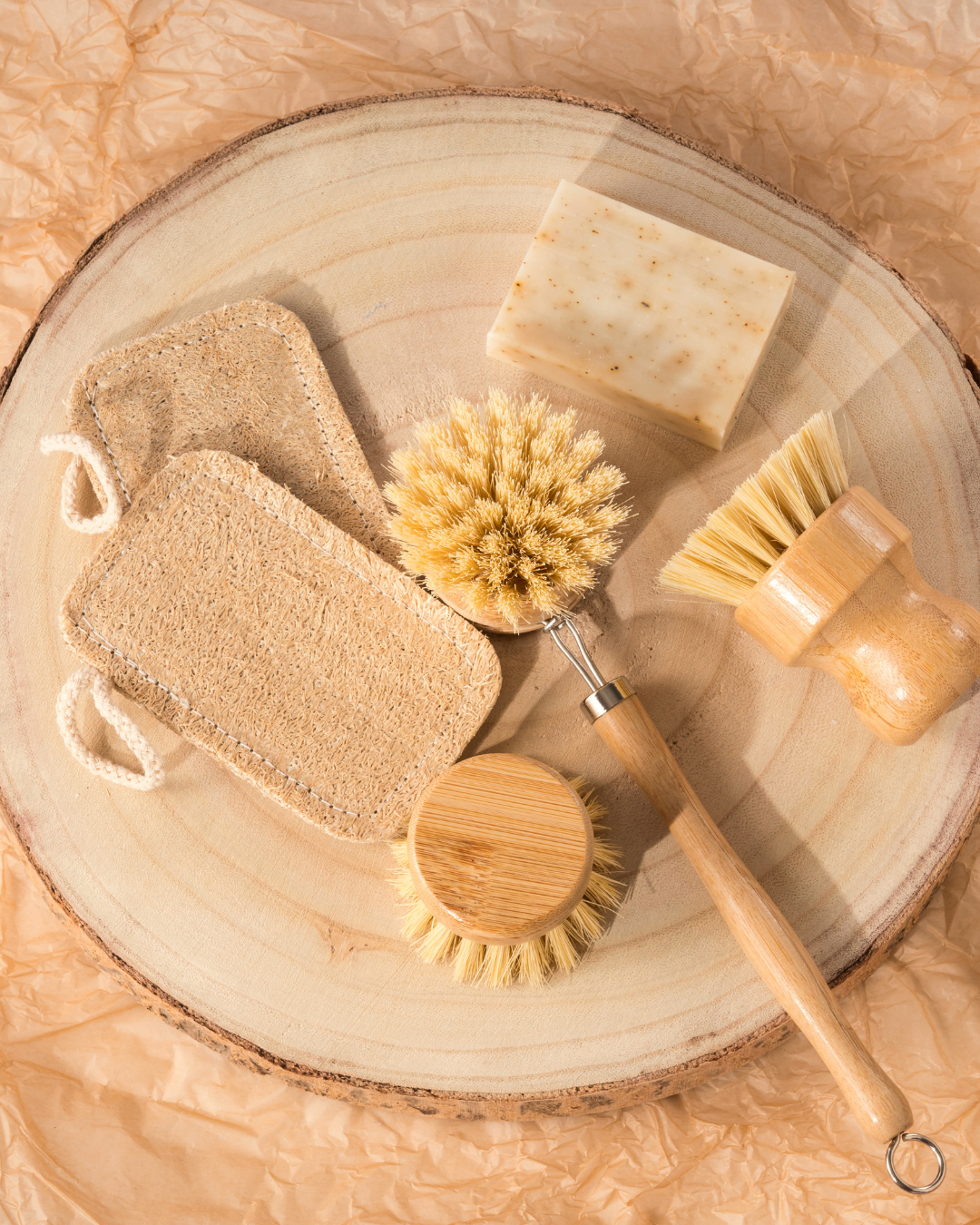 Set of natural cleaning tools including sponges, a scrubber, and a brush on a wooden surface.