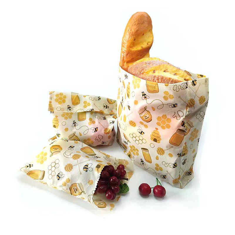 Patterned beeswax food wrap with bread and fruits on a white background
