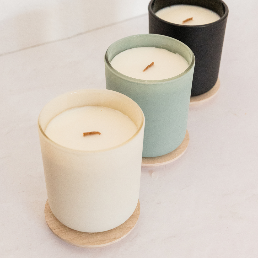 Three candles in pastel containers on a light surface