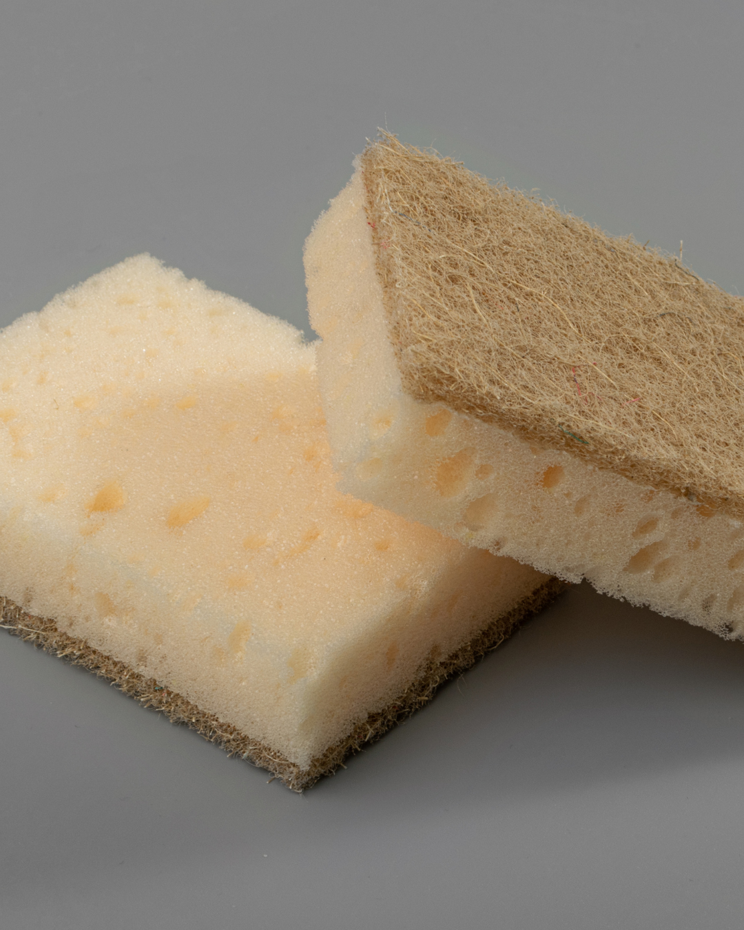 Two sponges, one beige and one brown, on a gray background